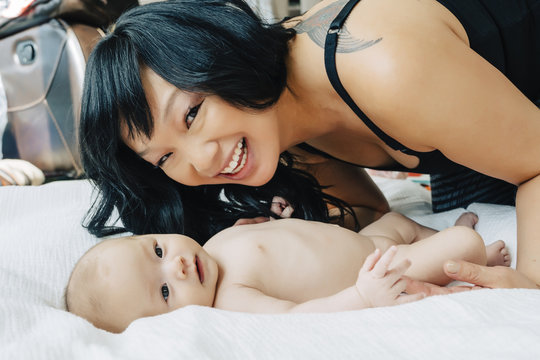 Portrait of mother with naked baby daughter on blanket