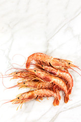 Raw shrimps on white marble with copyspace