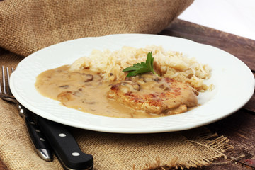 Delicious rice with chicken and vegetables on plate on wooden table