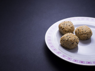 Japanese sesame mochi (sticky rice cakes) on small decorated plate isolated on dark background