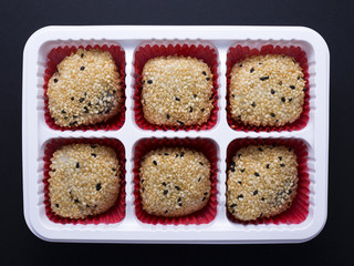 Japanese sesame mochi (sticky rice cakes) in white plastic tray isolated on dark background