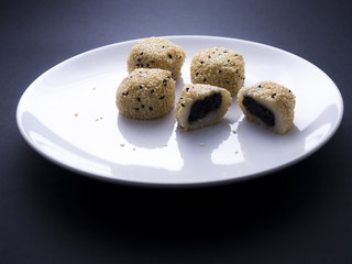 Japanese sesame mochi (sticky rice cakes) on white plate isolated on dark background