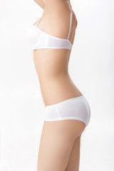 Fototapeta na wymiar female perfect sporty body in white lingerie on white background. healthy slim body of woman close up