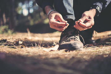 Tying the hiking boots of a hiker in the forset on mountian.