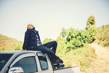 Men relax on car roof in the mountian.