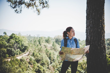 Young girl hiking standing relax and View map beside the tree.