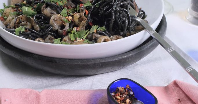 Dolly close up push in view of delivious black pasta with squids (cuttlefish) and ink