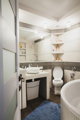 Fototapeta na wymiar Interior design of a luxury bathroom, washroom with washbasin (sink), bathtub, huge mirror and seashells on the shelf. Vertical