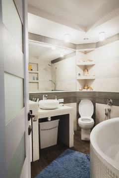 Interior design of a luxury bathroom, washroom with washbasin (sink), bathtub, huge mirror and seashells on the shelf. Vertical