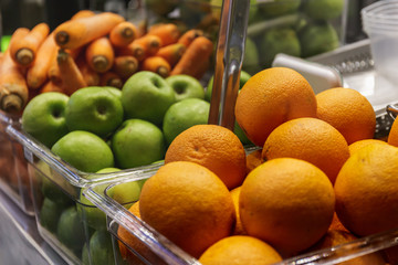 Oranges, apples, carrots in plastic containers
