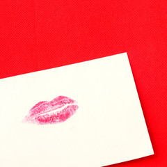 Card with red lips imprint on red background