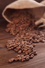 Coffee is poured from a burlap on a wooden background