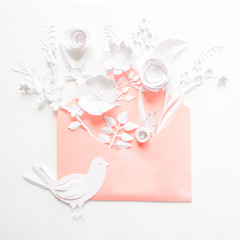 opened pink envelope full of varios white paper flowers on white background