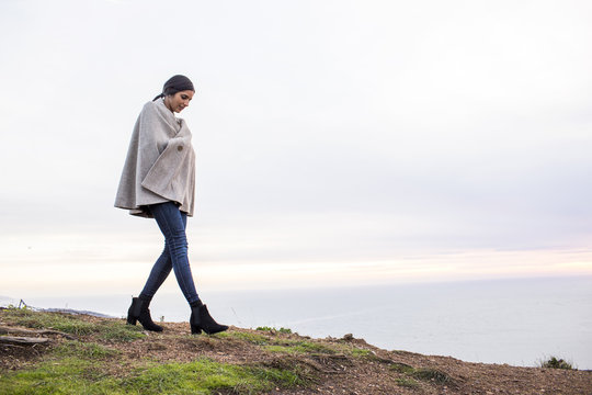 Indian woman wearing poncho walking on hill