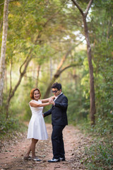 A couple in formal dress black suit and white dress romance dancing in the pine forest before wedding, Thailand