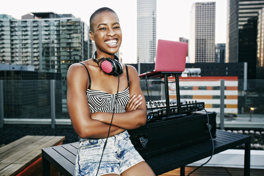 Smiling Black DJ relaxing on urban rooftop