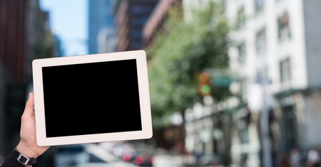 Cropped image of hand holding tablet computer in city