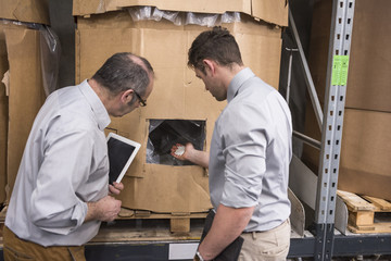 Two men examining product in factory warehouse