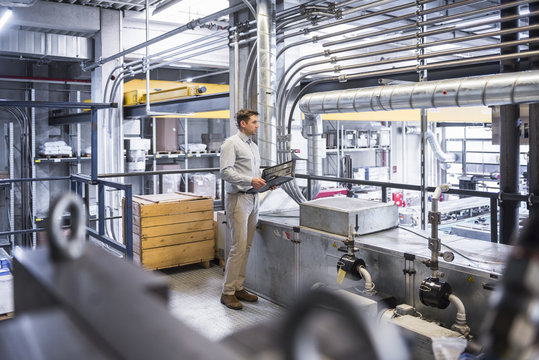 Man with documents looking on factory shop floor
