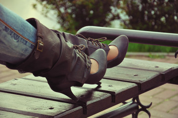 High brown leather shoes with laces and straps. Fashionable high-heeled shoes. Legs on the bench.
