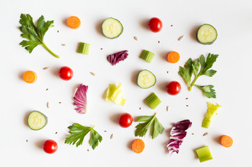 Eating pattern with raw ingredients of salad, lettuce leaves, cucumbers, red tomatoes, carrots, celery and seeds on white background
