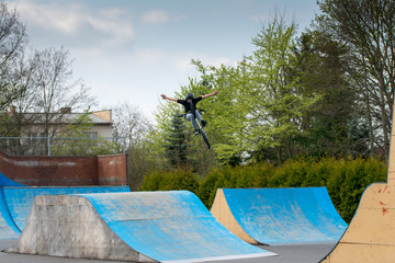 Young boy and high BMX jump in a skate park.
