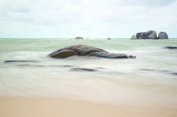 Natural rock formation in the sea and on a white sand beach in Belitung Island in the afternoon, Indonesia.