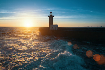 Fototapeta na wymiar Ocean surf on the Atlantic coast, near lighthouse during a beautiful sunset, Porto, Portugal.