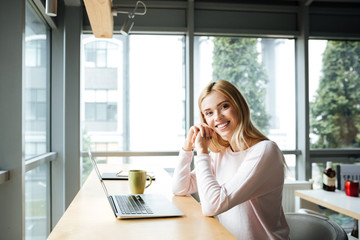 Happy lady sitting in office coworking while using laptop