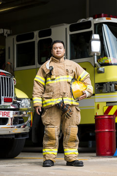 Portrait of firefighter standing near fire engine