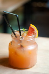 Lemonade with grapefruit. In a glass, jar with straws for drinking. Standing on a wooden table. A slice of grapefruit. 