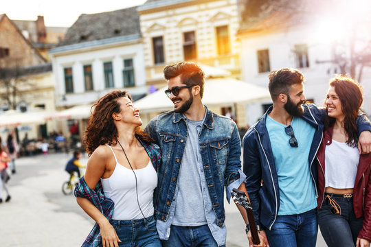 Group of friends laughing and walking at the city downtown.They embrace each other and smiling.