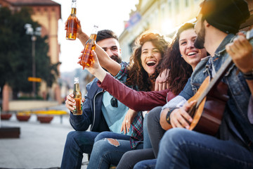 Group of young friends hangout on street in downtown.They standing by the city square,drinking and...