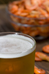 Glass of fresh beer with boil shrimps in glass bowl on background