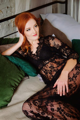 Redhead woman in black lace peignoir on the bed resting