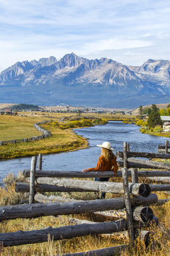 Caucasian woman leaning on wooden fence at mountain river