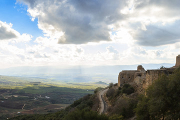 Fototapeta na wymiar Ancient knights fortress and amazing Upper Galilee mountains view, North Israel. Evening shot. Big grey rain clouds. Sunlight rays and shadows on the hills.