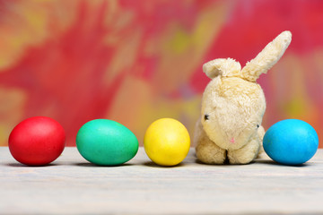 rabbit toy, painted easter eggs on colorful background