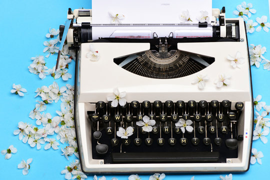 old vintage typewriter with paper and spring blossoming cherry flowers