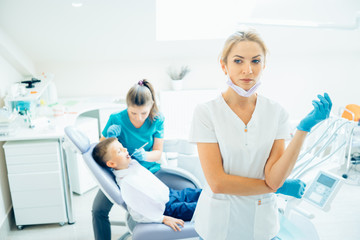 Fototapeta premium Dentist looking concerned in surgical mask standing with arms crossed at dental clinic