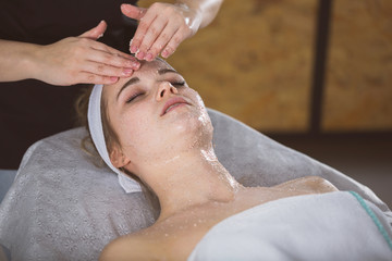 Obraz na płótnie Canvas Young woman during face salt scrub therapy