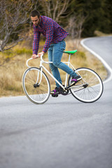 Fototapeta premium Cyclist man riding fixed gear sport bike in sunny day on a mountain road