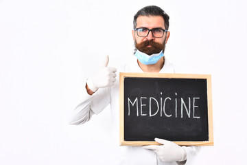 Bearded caucasian doctor holding syringe and board with Medicine inscription