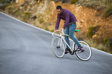 Fototapeta na wymiar Cyclist man riding fixed gear sport bike in sunny day on a mountain road