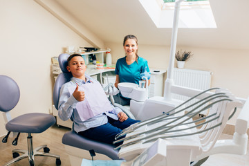 Obraz premium Handsome teenager boy giving thumbs up at dentist office