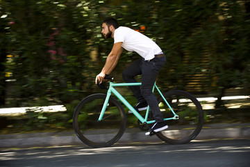 Cyclist man riding fixed gear sport bike in sunny day on a city