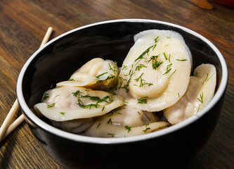 Meat dumplings - russian pelmeni, ravioli with meat on a wooden background