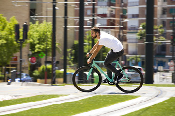 Cyclist man riding fixed gear sport bike in sunny day on a city