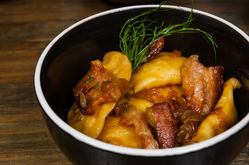 Dumplings with potatoes and bacon in a bowl on a wooden table
