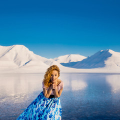 Girl slender beautiful red hair in a blue summer dress in the frost on a background of  mountains...